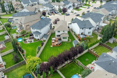 Rear exterior featuring a spacious wood deck, manicured lawn, and mature privacy plantings - 3922 Agar Court Sw, Edmonton, AB - Outdoor With View