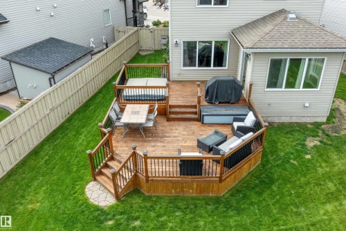 Multi-level wood deck featuring a built-in hot tub, black metal railings, and stone-look paver steps - 3922 Agar Court Sw, Edmonton, AB - Outdoor With Deck Patio Veranda With Exterior