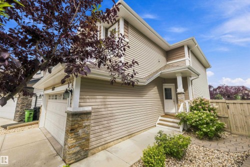 Siding exterior with stone accents, attached garage, covered entry, front porch with steps, and established landscaping - 3922 Agar Court Sw, Edmonton, AB - Outdoor