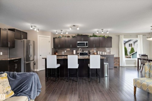 Kitchen featuring dark wood-finish cabinetry, stainless steel appliances, and a central island with bar seating - 3922 Agar Court Sw, Edmonton, AB - Indoor Photo Showing Kitchen With Upgraded Kitchen