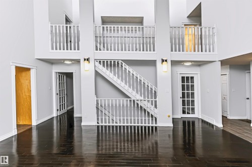 Vaulted ceilings, dark wood-finish flooring, white spindle railings, recessed lighting, and a white French door - 6016 177 Street Nw, Edmonton, AB - Indoor Photo Showing Other Room
