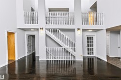 Vaulted ceilings, dark wood-finish flooring, white spindle railings, recessed lighting, and a white French door - 