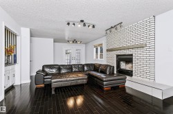 Dark wood-finish flooring, white painted brick fireplace with hearth, built-in white cabinetry, track lighting fixtures, and white French doors - 