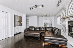 Dark wood-finish flooring, white painted brick fireplace with a mantel, built-in cabinetry, French doors, and track lighting fixtures - 