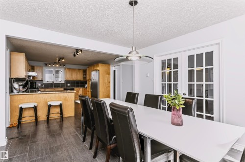 Open concept kitchen featuring wood-finish cabinetry, stainless steel appliances, and a breakfast bar - 6016 177 Street Nw, Edmonton, AB - Indoor Photo Showing Dining Room