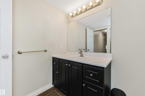 Vanity with dark cabinetry and brushed nickel hardware, white countertop with integrated sink, and a large wall mirror - 6016 177 Street Nw, Edmonton, AB - Indoor Photo Showing Bathroom