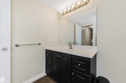 Vanity with dark cabinetry and brushed nickel hardware, white countertop with integrated sink, and a large wall mirror - 