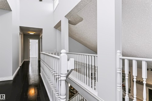 Upper-level hallway with dark wood-finish flooring, white baluster railings, and a flush-mount ceiling light - 6016 177 Street Nw, Edmonton, AB - Indoor Photo Showing Other Room