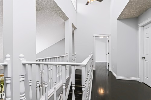 High ceilings with a ceiling fan, dark wood-finish flooring, white banister, and white paneled doors - 6016 177 Street Nw, Edmonton, AB - Indoor Photo Showing Other Room