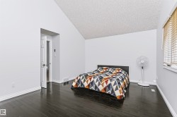 Vaulted ceiling, dark wood-finish flooring, white walls, white trim, and a window with blinds - 