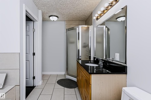 Vanity with dark countertop, large mirror, and overhead lighting - 6016 177 Street Nw, Edmonton, AB - Indoor Photo Showing Bathroom