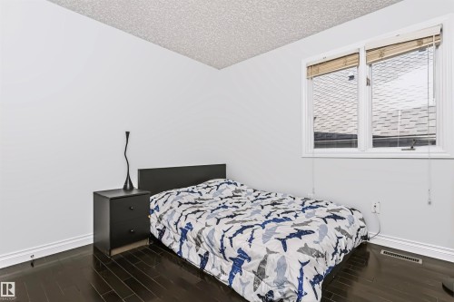 Dark wood-finish flooring with white walls - 6016 177 Street Nw, Edmonton, AB - Indoor Photo Showing Bedroom