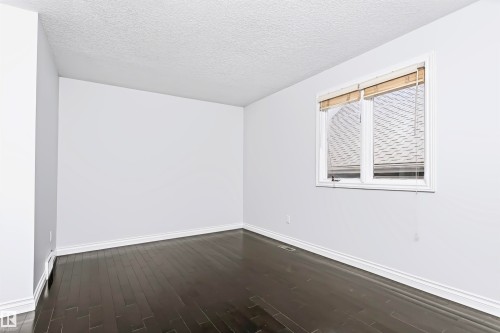 Wood-finish flooring with white trim, white walls, and a window with blinds - 6016 177 Street Nw, Edmonton, AB - Indoor Photo Showing Other Room