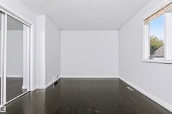 Dark wood-finish flooring, white trim, and a window with a white frame - 
