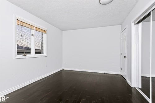 Dark wood-finish flooring, white trim, and a window with blinds - 6016 177 Street Nw, Edmonton, AB - Indoor Photo Showing Other Room
