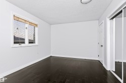 Dark wood-finish flooring, white trim, and a window with blinds - 