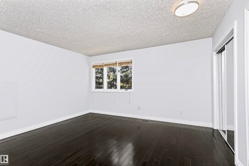 Dark wood-finish flooring, white trim, and a window with blinds - 6016 177 Street Nw, Edmonton, AB - Indoor Photo Showing Other Room