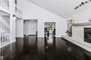 Vaulted ceilings, dark wood-finish flooring, white brick fireplace with a mantel, and a multi-level staircase with white balusters - 6016 177 Street Nw, Edmonton, AB  - Indoor With Fireplace 