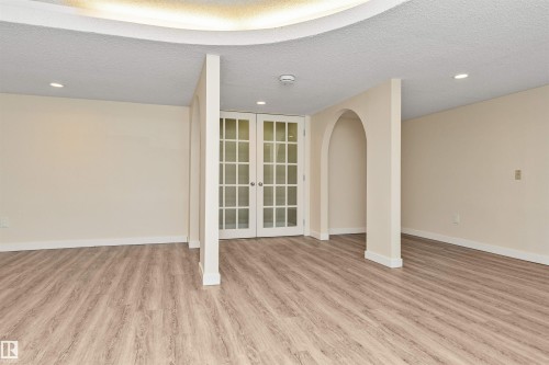 Recessed lighting, wood-finish flooring, interior french doors, arched doorways, and a tray ceiling - 6016 177 Street Nw, Edmonton, AB - Indoor Photo Showing Other Room