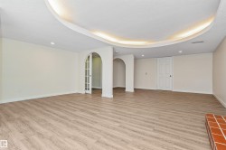Spacious room featuring wood-finish flooring, recessed lighting, and a cove ceiling with accent lighting - 