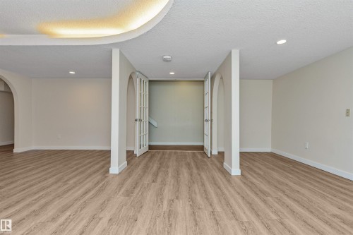 Wood-finish flooring throughout, recessed lighting, arched doorways, and double French doors - 6016 177 Street Nw, Edmonton, AB - Indoor Photo Showing Other Room