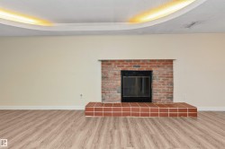 Recessed lighting in a curved ceiling feature, brick fireplace with a tile hearth, and wood-finish flooring - 
