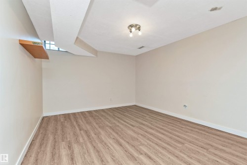 Wood-finish flooring, neutral wall tones, recessed window, ceiling-mounted light fixture, and a built-in wall shelf - 6016 177 Street Nw, Edmonton, AB - Indoor Photo Showing Other Room