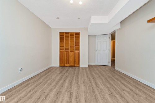 Neutral wall finishes, wood-finish flooring, white trim, wood bi-fold closet doors, and recessed ceiling lighting - 6016 177 Street Nw, Edmonton, AB - Indoor Photo Showing Other Room