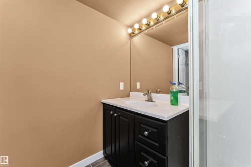 Vanity with a white countertop and integrated sink, a large wall-mounted mirror, and overhead vanity lighting - 6016 177 Street Nw, Edmonton, AB - Indoor Photo Showing Bathroom