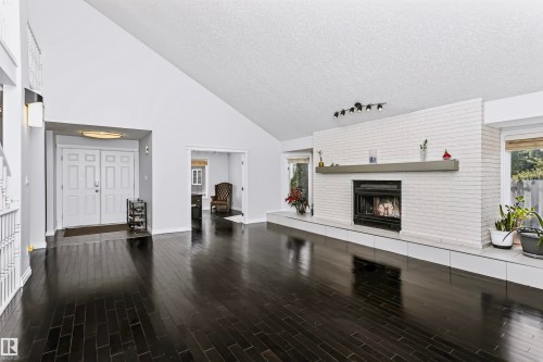 Vaulted ceiling, dark wood-finish flooring, white brick fireplace, recessed lighting, and double entry doors - 6016 177 Street Nw, Edmonton, AB - Indoor With Fireplace