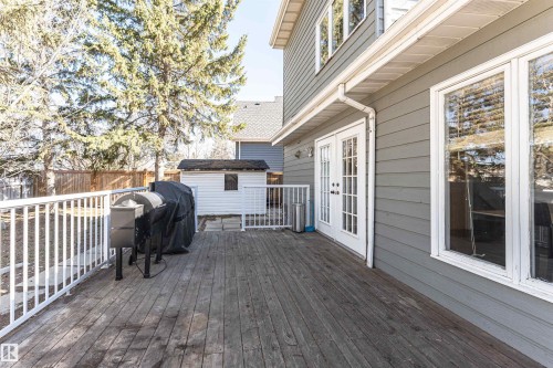 Expansive wood deck with white railing, featuring double French doors and a storage shed within the fenced yard - 6016 177 Street Nw, Edmonton, AB - Outdoor With Deck Patio Veranda With Exterior