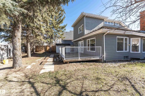 Rear exterior featuring gray siding, a wood deck with white railings, multiple windows, and a storage shed - 6016 177 Street Nw, Edmonton, AB - Outdoor