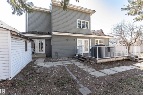 Rear exterior featuring gray siding, a raised wood deck with white railings, and two sets of double French doors - 6016 177 Street Nw, Edmonton, AB - Outdoor With Deck Patio Veranda