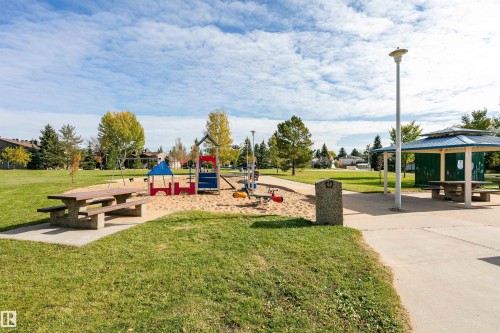 Expansive green space featuring a playground with sand, concrete picnic tables, mature trees, and a covered picnic area - 6016 177 Street Nw, Edmonton, AB - Outdoor