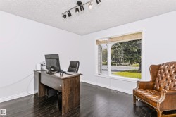 Dark wood-finish flooring with white baseboards, bright white walls, and a large window with natural light - 