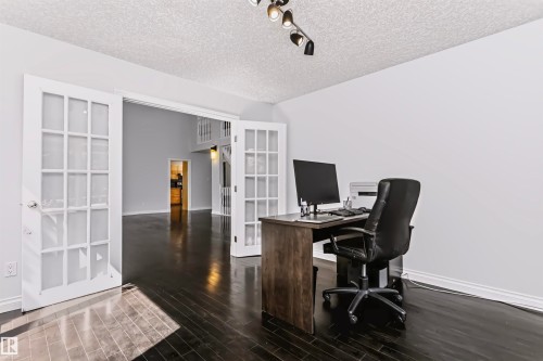 Double French doors with glass panes, dark wood-finish flooring, white walls, and track lighting - 6016 177 Street Nw, Edmonton, AB - Indoor Photo Showing Office