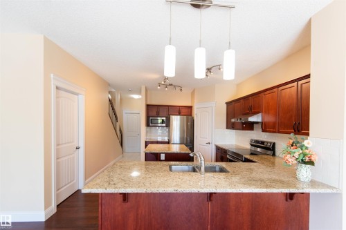 Kitchen featuring rich wood cabinetry, stainless steel appliances, light-toned countertops, and a white subway tile backsplash - 1419 Chahley Place Nw, Edmonton, AB - Indoor Photo Showing Kitchen With Double Sink With Upgraded Kitchen