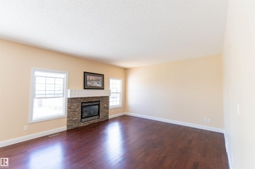 Dark wood-finish flooring, light-toned walls, and white trim - 1419 Chahley Place Nw, Edmonton, AB - Indoor Photo Showing Living Room With Fireplace
