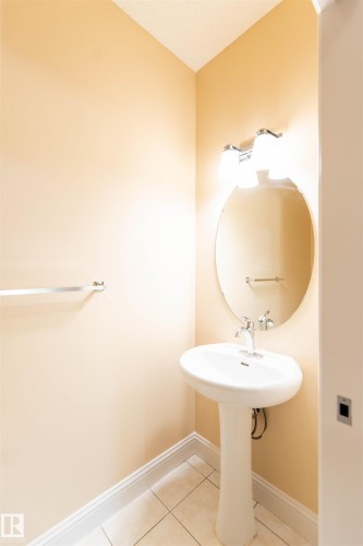 Pedestal sink with chrome faucet, oval wall mirror, and vanity lighting fixture - 1419 Chahley Place Nw, Edmonton, AB - Indoor Photo Showing Bathroom