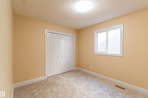 Carpeted room featuring a white bi-fold closet, a double-hung window with white blinds, and a flush mount ceiling light fixture - 1419 Chahley Place Nw, Edmonton, AB - Indoor Photo Showing Other Room