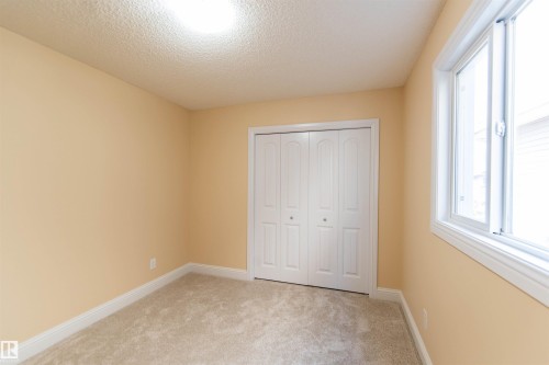 Neutral-toned wall finish, recessed ceiling lighting, carpeted flooring, white bi-fold closet doors, and a double-pane window - 1419 Chahley Place Nw, Edmonton, AB - Indoor Photo Showing Other Room