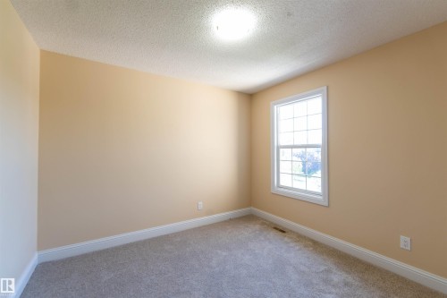 Carpeted flooring, neutral wall tones, white trim, and a double-hung window with grilles - 1419 Chahley Place Nw, Edmonton, AB - Indoor Photo Showing Other Room