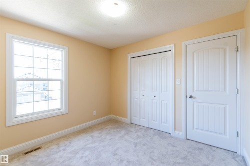 Neutral wall tones, white trim, light-colored carpeting, white interior door, and a white bi-fold closet door - 1419 Chahley Place Nw, Edmonton, AB - Indoor Photo Showing Other Room