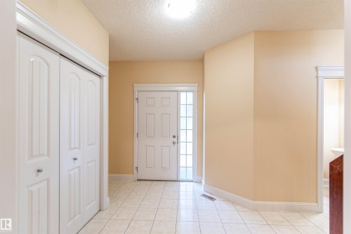 Tiled flooring extending throughout, bi-fold closet doors, and a front entry door with a sidelight - 1419 Chahley Place Nw, Edmonton, AB - Indoor Photo Showing Other Room