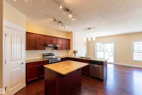Hardwood-finish flooring, cherry-finish cabinetry, stainless steel appliances, granite countertops, and a subway tile backsplash - 1419 Chahley Place Nw, Edmonton, AB - Indoor Photo Showing Kitchen