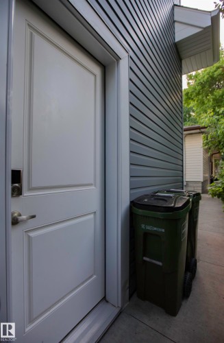 White paneled exterior door with brushed nickel hardware, set against dark gray horizontal siding - 11131 52 Street Nw, Edmonton, AB - Outdoor With Exterior