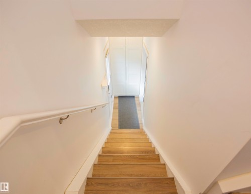 Staircase featuring wood-finish treads, a white handrail, and white walls - 11131 52 Street Nw, Edmonton, AB - Indoor Photo Showing Other Room