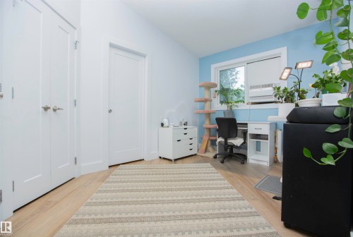 Interior room featuring light wood-finish flooring, white panel doors, and a double window with white trim - 11131 52 Street Nw, Edmonton, AB - Indoor Photo Showing Other Room