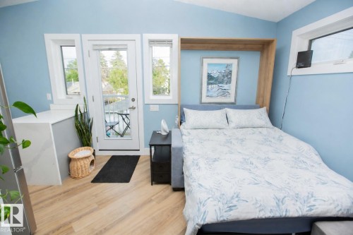 Integrated wall bed system with neutral-toned wood-finish flooring - 11131 52 Street Nw, Edmonton, AB - Indoor Photo Showing Bedroom