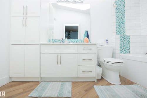 Contemporary bathroom featuring white cabinetry, a spacious vanity with a white countertop, and a built-in bathtub - 11131 52 Street Nw, Edmonton, AB - Indoor Photo Showing Bathroom